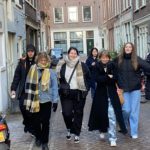 En gjeng smilende studenter side om side i en gate i Amsterdam.