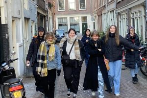 En gjeng smilende studenter side om side i en gate i Amsterdam.